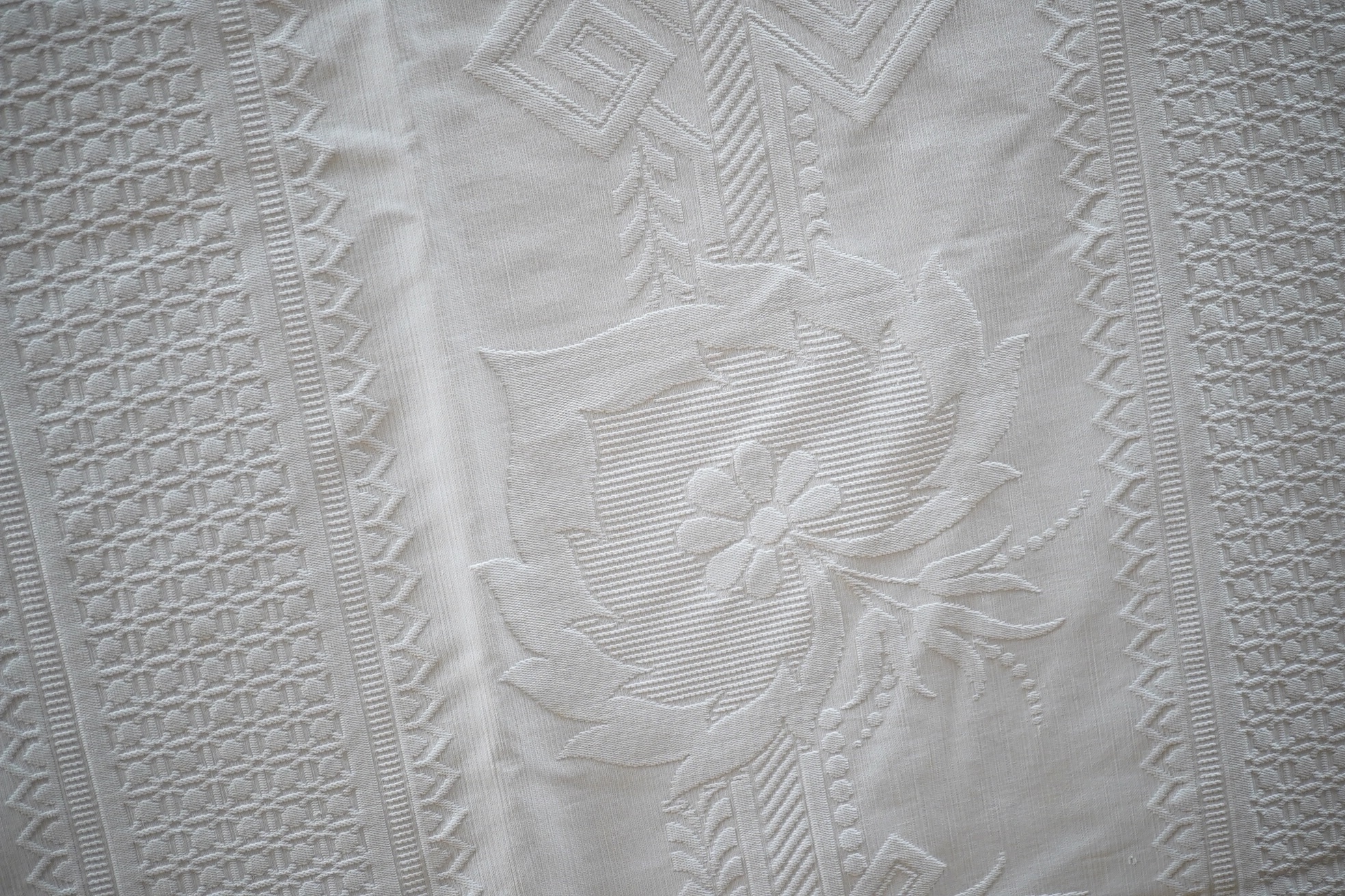 Three inspired Christopher Dresser white linen embossed bedcovers, with wide borders and ornate central designs, 216cm x 208cm. Condition - all good but will need rewashing.